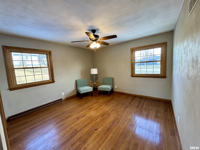 unfurnished room featuring hardwood / wood-style flooring, ceiling fan, a healthy amount of sunlight, and a baseboard radiator