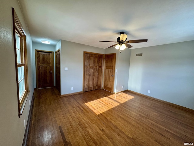 unfurnished bedroom with hardwood / wood-style flooring, ceiling fan, and multiple windows