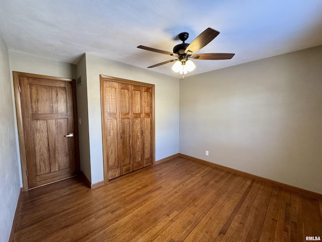 unfurnished bedroom featuring wood-type flooring, a closet, and ceiling fan