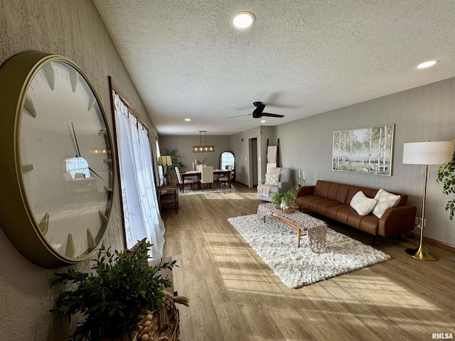 living room with wood-type flooring, a textured ceiling, and ceiling fan