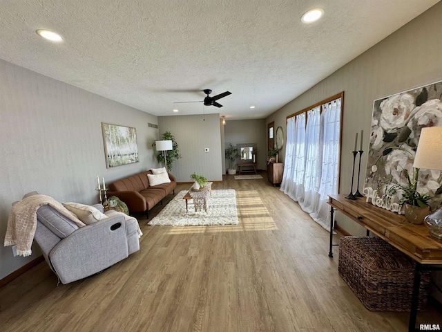 living room with ceiling fan, light hardwood / wood-style floors, and a textured ceiling