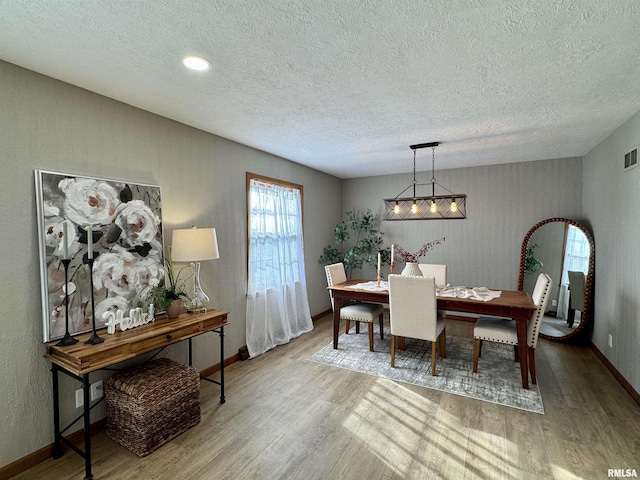 dining room featuring a textured ceiling and light hardwood / wood-style flooring