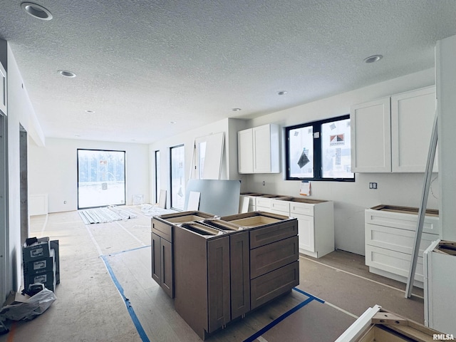 kitchen featuring dark brown cabinets, a center island, white cabinetry, and a textured ceiling