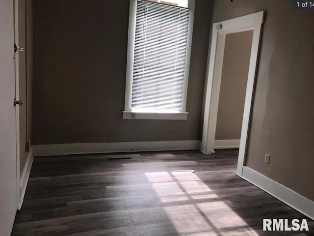 empty room with dark hardwood / wood-style floors and plenty of natural light