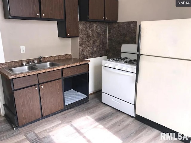 kitchen featuring backsplash, dark brown cabinets, white appliances, sink, and light hardwood / wood-style floors