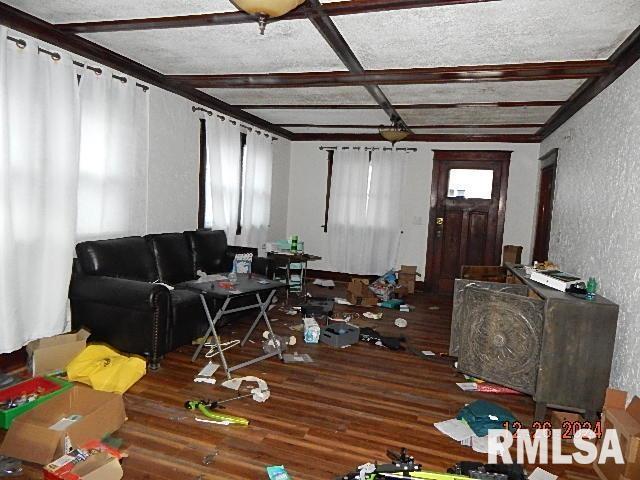 living room with beamed ceiling, wood-type flooring, and a textured ceiling