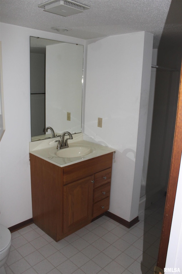 bathroom with tile patterned flooring, vanity, a textured ceiling, and toilet