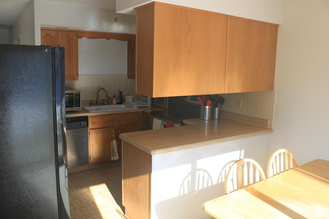 kitchen featuring kitchen peninsula, decorative backsplash, sink, and appliances with stainless steel finishes