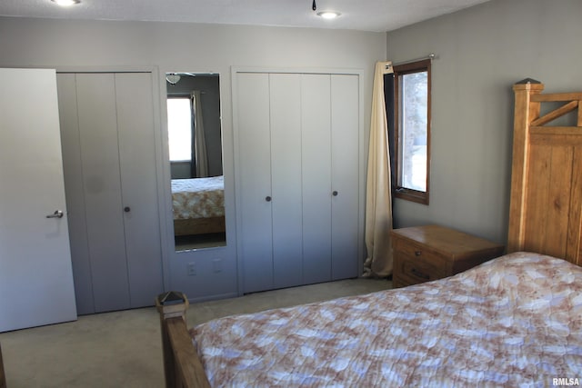 bedroom featuring multiple closets and light carpet