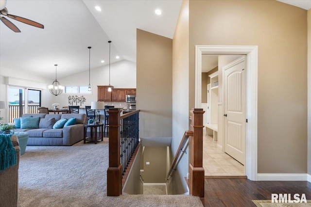 interior space with baseboards, recessed lighting, ceiling fan with notable chandelier, wood finished floors, and high vaulted ceiling