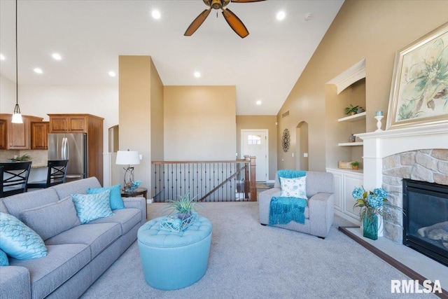 carpeted living room with built in features, recessed lighting, a fireplace, arched walkways, and high vaulted ceiling