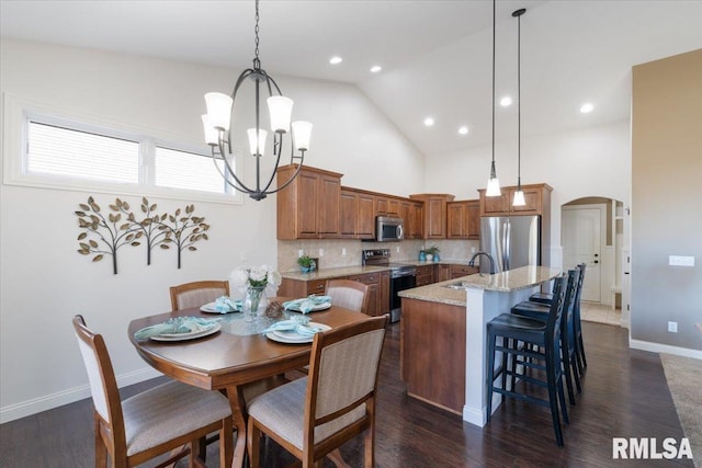 kitchen featuring backsplash, light stone countertops, brown cabinets, arched walkways, and stainless steel appliances