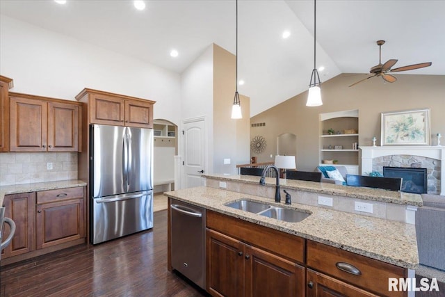 kitchen with dark wood-type flooring, a sink, open floor plan, stainless steel appliances, and a fireplace