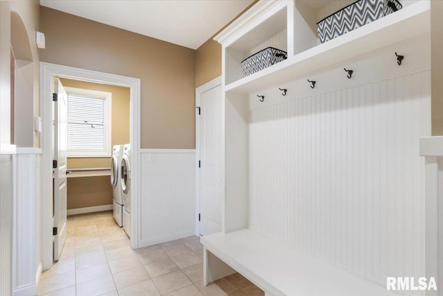 mudroom with wainscoting, light tile patterned floors, and washing machine and dryer