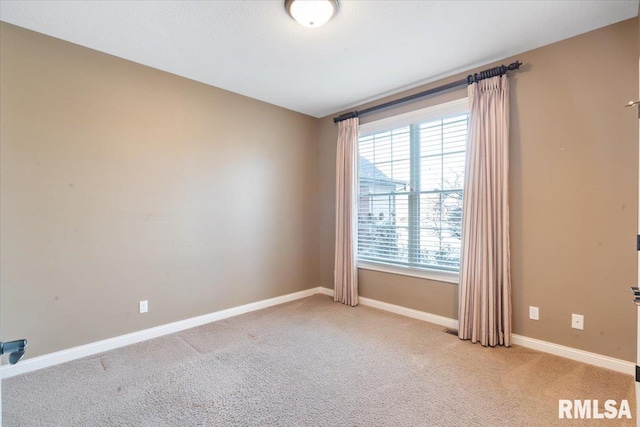 empty room featuring baseboards and light carpet