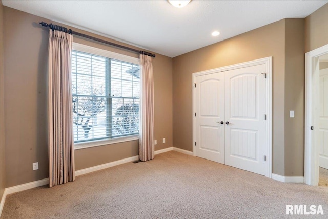 unfurnished bedroom featuring baseboards and light carpet