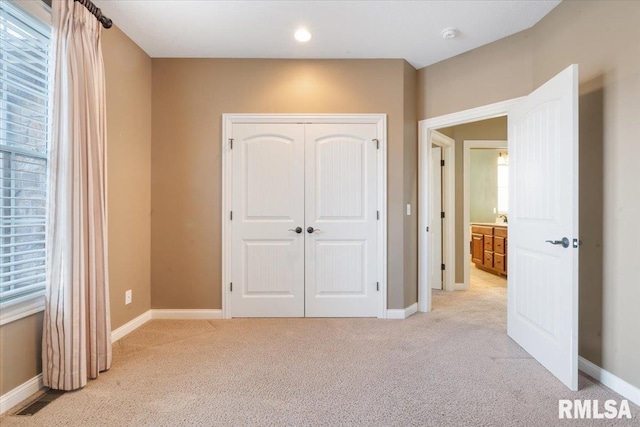 unfurnished bedroom with visible vents, light colored carpet, baseboards, and a closet