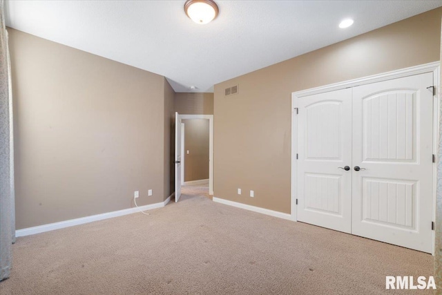 unfurnished bedroom with visible vents, baseboards, light carpet, and a closet