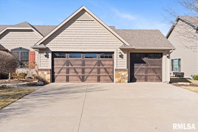 view of front of house featuring driveway, a garage, stone siding, and a shingled roof