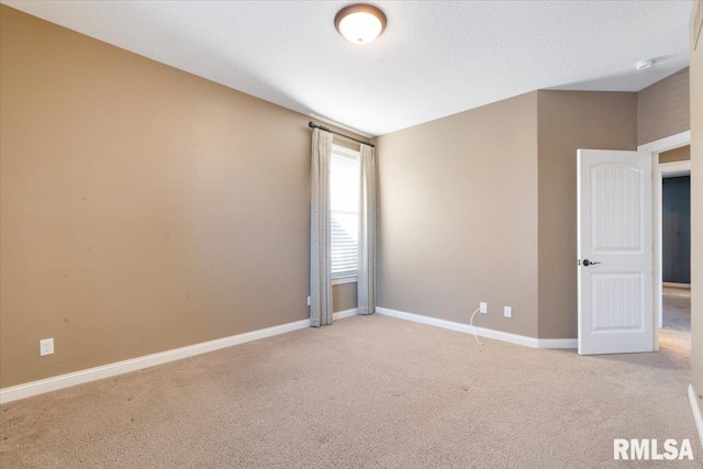 empty room featuring baseboards, a textured ceiling, and light carpet