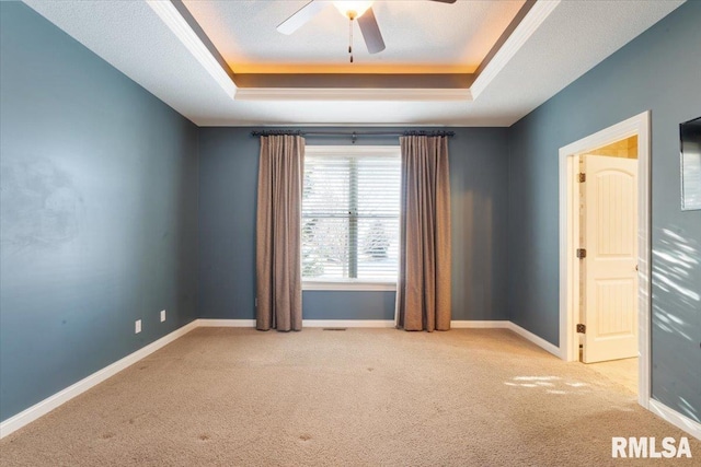 carpeted empty room with a tray ceiling, baseboards, a textured ceiling, and a ceiling fan