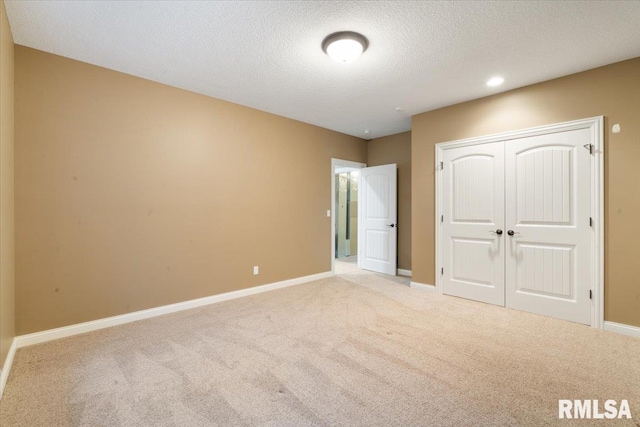 unfurnished bedroom featuring a closet, a textured ceiling, baseboards, and carpet floors