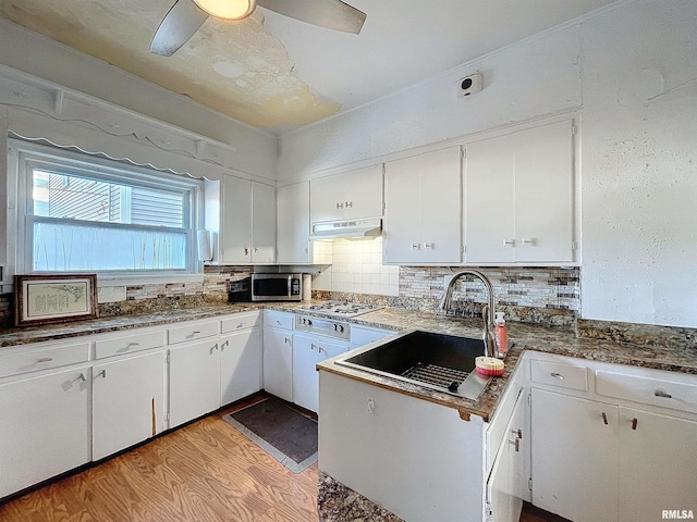 kitchen with tasteful backsplash, sink, light wood-type flooring, stainless steel appliances, and white cabinets