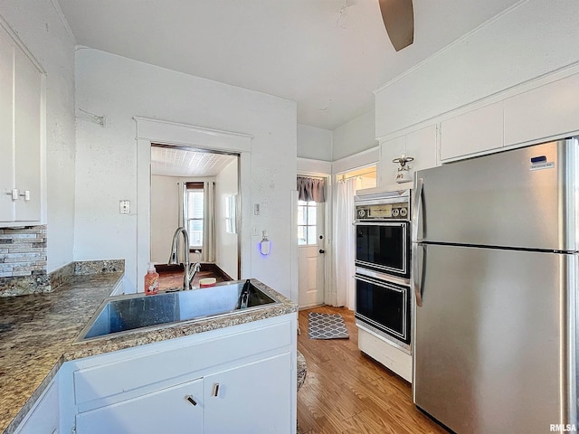 kitchen featuring white cabinets, stainless steel fridge, and sink