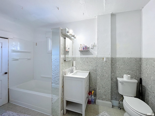 bathroom with a tub, tile walls, toilet, and vanity