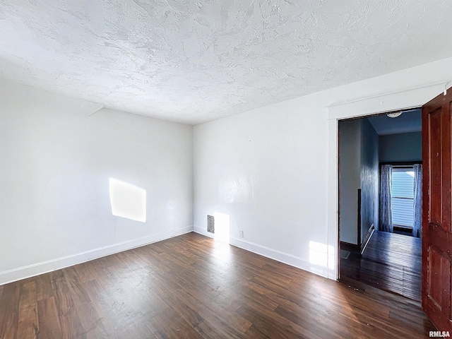 empty room with hardwood / wood-style flooring and a textured ceiling