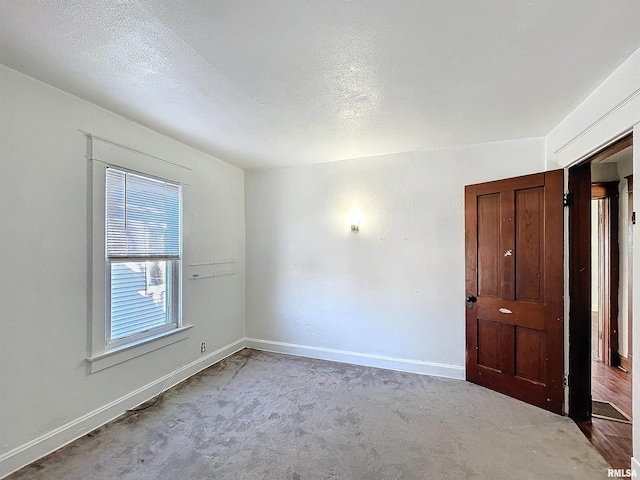 carpeted empty room featuring a textured ceiling