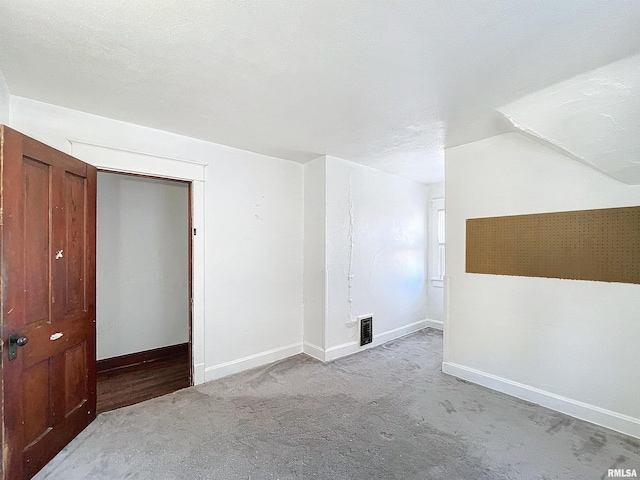 interior space featuring a textured ceiling, lofted ceiling, and light colored carpet