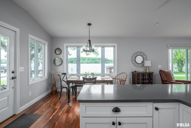 kitchen with lofted ceiling, a wealth of natural light, white cabinets, and decorative light fixtures