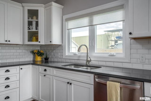 kitchen with white cabinets, tasteful backsplash, stainless steel dishwasher, and sink