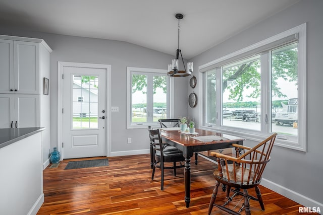 dining room featuring dark hardwood / wood-style floors, vaulted ceiling, and a notable chandelier