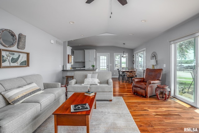 living room with a wealth of natural light, light hardwood / wood-style floors, vaulted ceiling, and ceiling fan