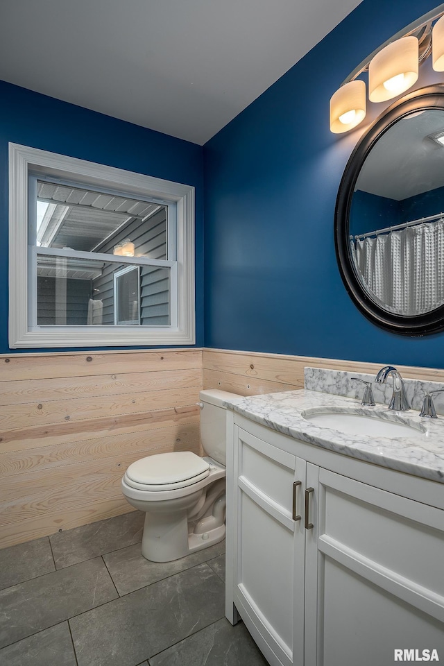 bathroom featuring vanity, wood walls, tile patterned floors, a shower with shower curtain, and toilet