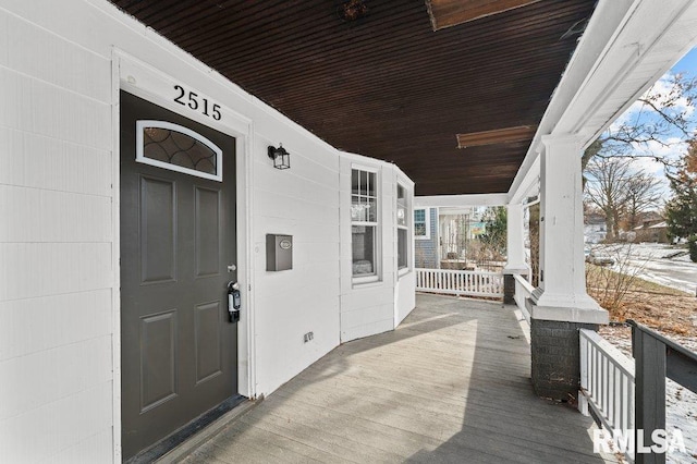 snow covered property entrance with covered porch