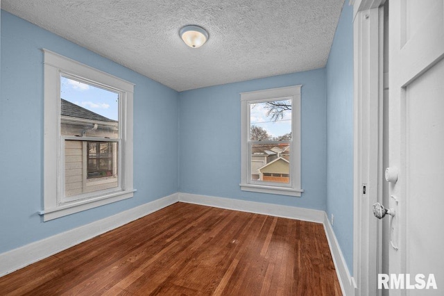 unfurnished room featuring plenty of natural light, wood-type flooring, and a textured ceiling