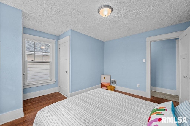 bedroom featuring dark hardwood / wood-style flooring and a textured ceiling