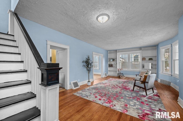 living room featuring hardwood / wood-style floors, a textured ceiling, and built in features