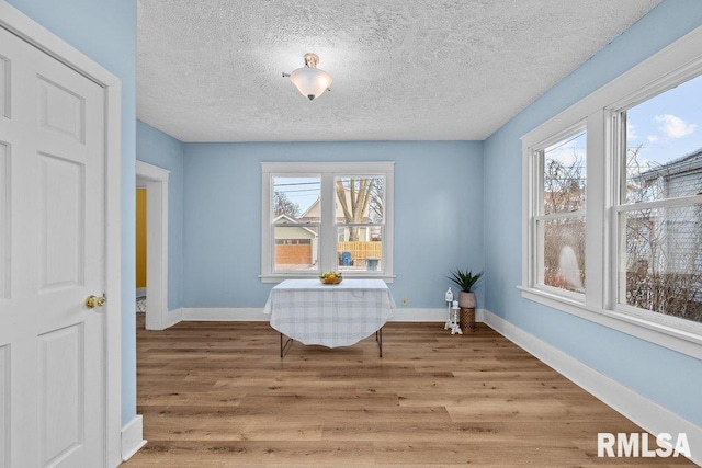 living area with a textured ceiling, hardwood / wood-style flooring, and a healthy amount of sunlight