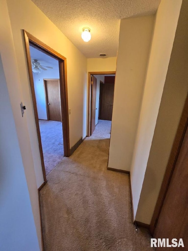 hall with a textured ceiling and light carpet