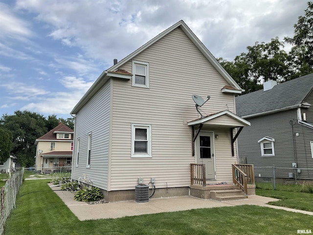 back of house with central air condition unit and a yard