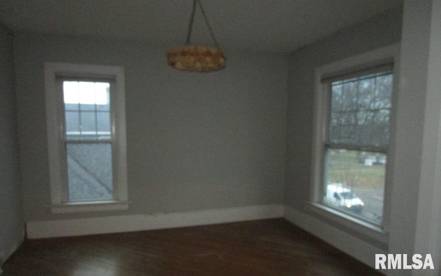 spare room with baseboards and wood finished floors