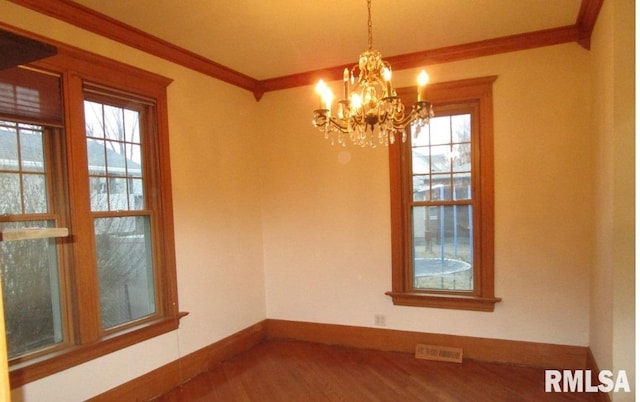 spare room featuring ornamental molding, visible vents, plenty of natural light, and wood finished floors