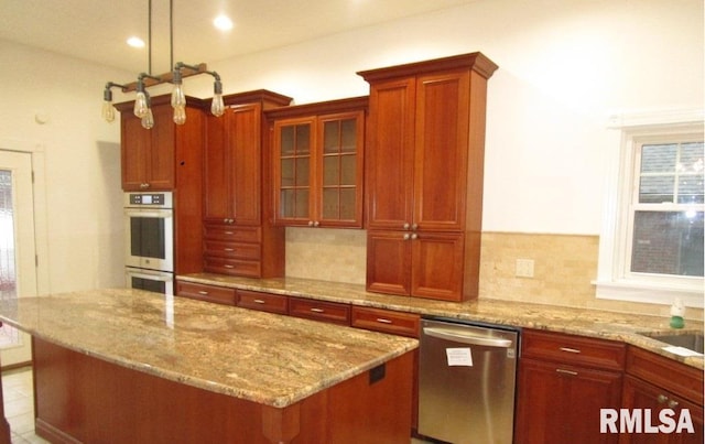 kitchen with stainless steel appliances, a kitchen island, backsplash, light stone countertops, and glass insert cabinets