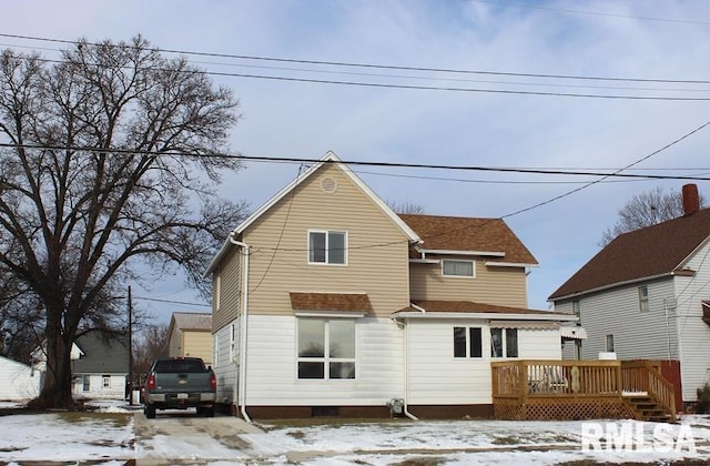 snow covered rear of property with a deck