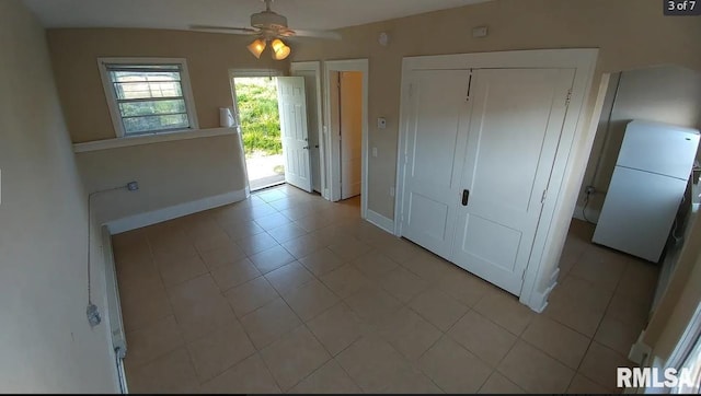 interior space featuring ceiling fan, white fridge, access to outside, a closet, and light tile patterned floors