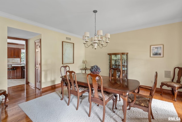 dining room featuring light hardwood / wood-style flooring, an inviting chandelier, and crown molding